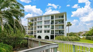 A multi-story hotel with balconies, a wooden deck, and a view of the surrounding greenery. - Oceanfront Condominium with Gorgeous Ocean Views. (Saint Simons Island)