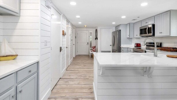 A modern kitchen with white cabinetry, a central island, and a microwave above the stove. - Oceanfront Condominium with Pool. Pet Friendly. (Saint Simons Island)