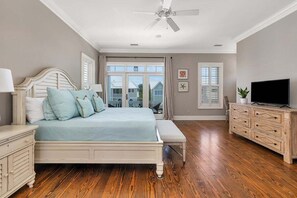 A bedroom with a bed, bedside tables, a TV, and a ceiling fan.
