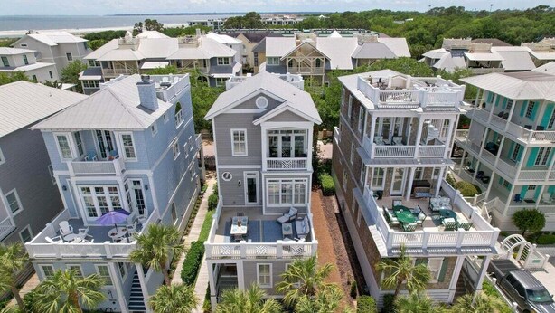 Una zona residencial costera con varias casas de dos pisos, balcones, espacios para sentarse al aire libre y vista al océano.