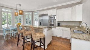 Una cocina moderna con gabinetes blancos, electrodomésticos de acero inoxidable y una encimera de granito.