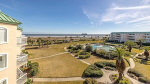 Un hôtel doté d’une piscine, de palmiers et offrant une vue sur la plage.