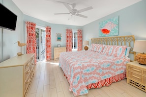 A bedroom with a bed, a dresser, a nightstand, a ceiling fan, and a television.