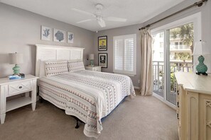 A bedroom with a bed, a nightstand, a dresser, a ceiling fan, and a window with curtains.