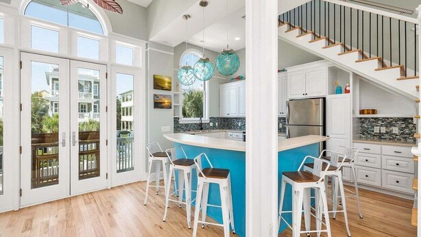 Una cocina amplia con una isla grande, armarios blancos y una pared de acento azul.