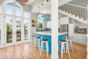 A spacious kitchen with a large island, white cabinetry, and a blue accent wall.