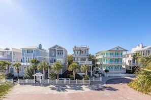 A beachfront property with multiple-story buildings, a paved walkway, and palm trees.
