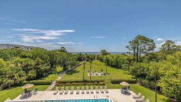 Relax by the pool with a clear ocean view, surrounded by lounge chairs and umbrellas.