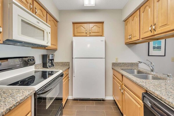 Una cocina compacta equipada con microondas, estufa, refrigerador y lavavajillas.