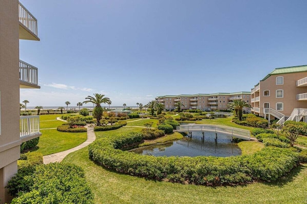 A hotel courtyard with a central pond, pathways, and a bridge.