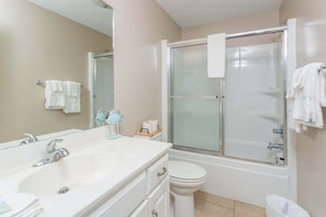 A bathroom with a sink, mirror, toilet, and a glass-enclosed shower.