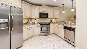A modern kitchen with stainless steel appliances, white cabinetry, and a granite countertop. - Half a Mile to the Pier and Village! (Saint Simons Island)