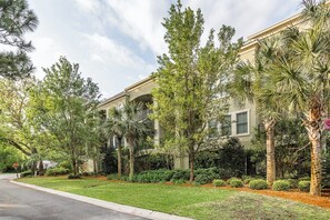 A residential building with a well-maintained lawn, palm trees, and a stop sign.