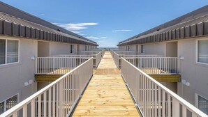 A corridor leading to a beach with two-story buildings on either side. - Oceanfront Condo with Balcony, Pool, Beach Access (Saint Simons Island)