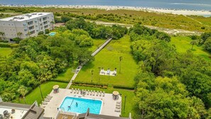 A resort with a swimming pool, lounge area, and a view of the beach and ocean. - Oceanfront Condo with Balcony, Pool, Beach Access (Saint Simons Island)