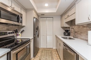 Enjoy cooking and meal preparation in this well-equipped kitchen with a sink, dishwasher, microwave, and oven.