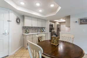 Enjoy cooking and dining in this stylish kitchen with a central island, white cabinetry, and a round dining table.