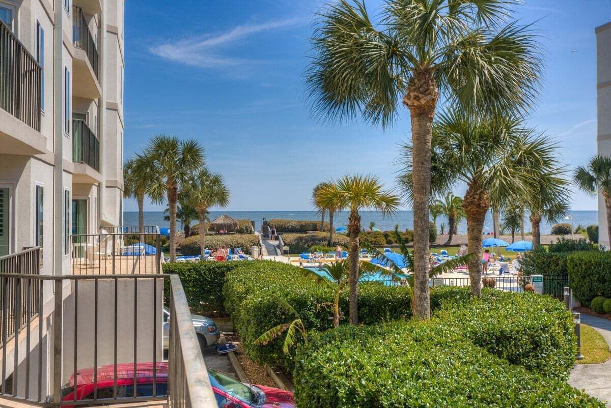 Een resort met een zwembad, palmbomen en uitzicht op zee.