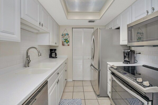 A modern kitchen with white cabinetry, a stainless steel refrigerator, a built-in oven, and a microwave. - Golden Isles Spacious Beachfront Condo (Saint Simons Island)