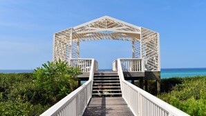 A wooden walkway leading to a white arched structure with a clear view of the ocean. - Three Houses Down From Beach In Seaside, FL, Double Lot + 2 Adult Bikes! (Santa Rosa Beach)
