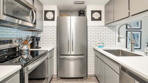 Cozinha moderna com eletrodomésticos de aço inoxidável, azulejos brancos tipo metrô e uma pia dupla.