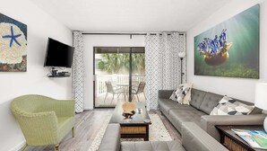 Uma sala de estar com sofá, poltrona, mesa de centro e obras de arte.