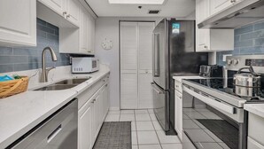 A modern kitchen with white cabinets, a built-in oven, a microwave, and a stainless steel refrigerator. - Oceanfront and Great Amenities! (Saint Simons Island)