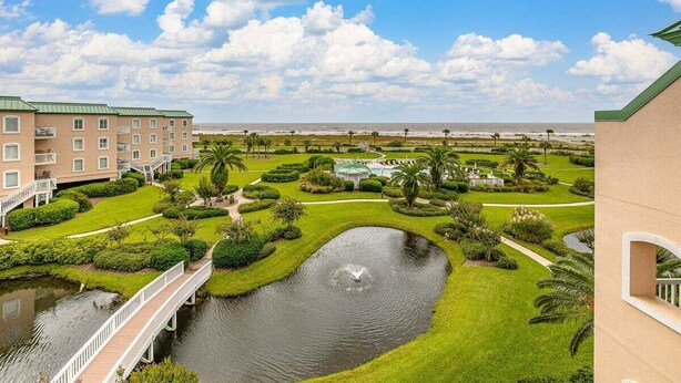 A hotel with a pool, a bridge, and a well-maintained garden with palm trees. - Beachfront Condo, Room for Multiple Families! (Saint Simons Island)
