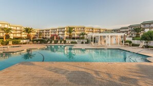 A hotel with a swimming pool, palm trees, and a covered area. - Beachfront Condo, Room for Multiple Families! (Saint Simons Island)