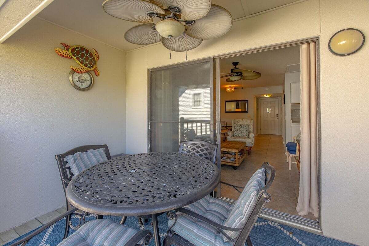 A sunroom with a round table and chairs, a ceiling fan, and a decorative turtle wall art piece.