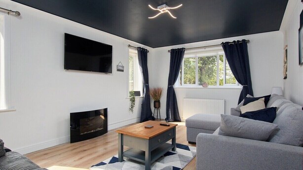 Una sala de estar moderna con chimenea, televisor de pantalla plana y sofá gris.