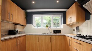 Una cocina con armarios de madera, ventana, pileta y estufa.