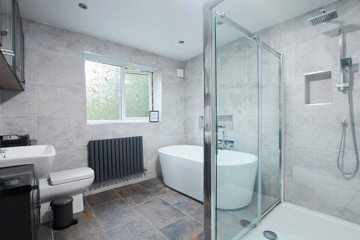 A modern bathroom with a glass-enclosed shower, a freestanding bathtub, and a toilet.