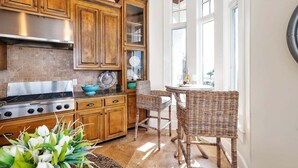 A kitchen with wooden cabinets, a stainless steel stove, and a wicker dining table. - Luxurious Complex, Ocean Views. Steps from Beach. (Saint Simons Island)