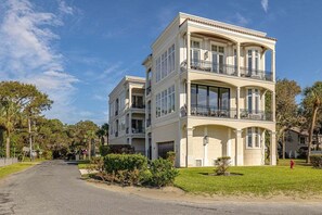Un edificio de varios pisos con balcones, ventanas amplias y un césped bien cuidado.