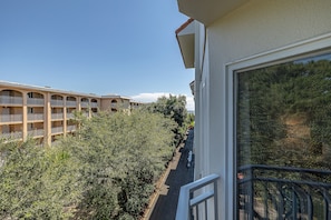 Residential building with a balcony overlooking lush greenery.