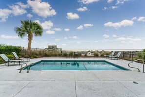 Relax by the serene pool surrounded by lounge chairs and a palm tree.