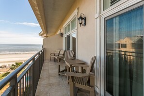 Relax on the balcony with a view of the beach, featuring a comfortable seating area and lanterns for ambiance.
