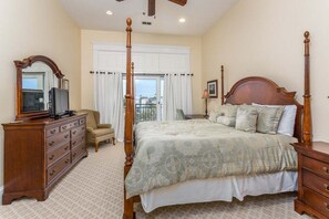A bedroom with a four-poster bed, wooden dresser, and a television on a cabinet.