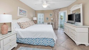 A bedroom with a bed, nightstands, a dresser, a television, and a ceiling fan. - Spacious Oceanfront Condominium on St Simons! (Saint Simons Island)