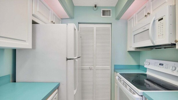A compact kitchen with white cabinetry, a built-in microwave, a stove, and a dishwasher.