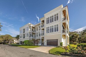 A multi-story residential building with a central courtyard, multiple balconies, and a garage. - Luxurious Complex. Steps from the Beach! (Saint Simons Island)