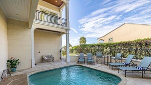 A swimming pool with lounge chairs and a covered seating area. - Luxurious Complex. Steps from the Beach! (Saint Simons Island)