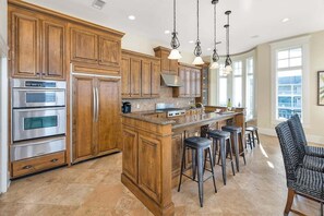 A spacious kitchen with wooden cabinets, stainless steel appliances, and a central island with bar stools.