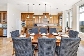 A spacious kitchen with wooden cabinets, a central island, and a dining area with wicker chairs. - Luxurious Complex. Steps from the Beach! (Saint Simons Island)