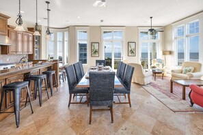 A spacious kitchen with a dining area, large windows, and a view of the ocean.