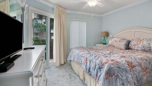 A bedroom with a bed, a TV, a ceiling fan, and a view of the outdoors. - Oceanfront Resort with Pool, Tennis and Fitness Ce (Saint Simons Island)