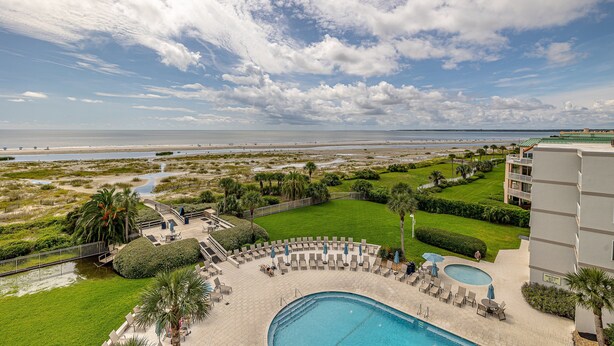 A resort with a pool, lounge chairs, and a view of the beach. - Oceanfront Condo with community pool! (Saint Simons Island)
