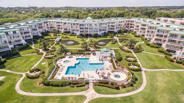 Un grand hôtel doté de nombreux balcons, d’une piscine centrale et de jardins magnifiquement entretenus.