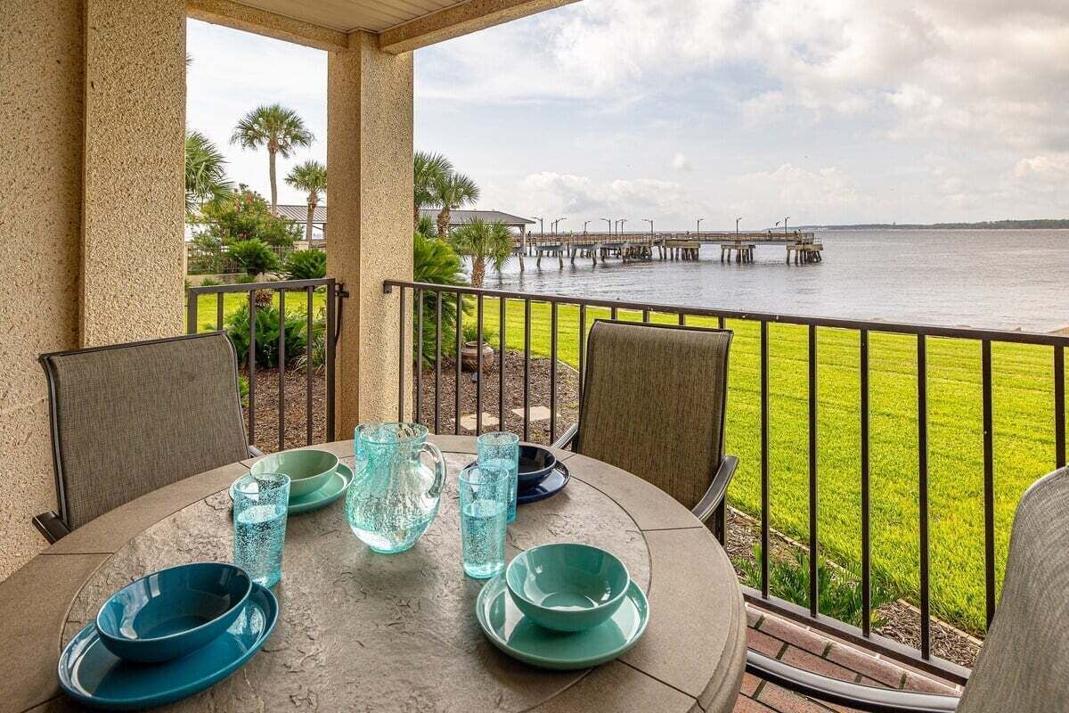 A covered outdoor dining area with a view of a water body and a pier.